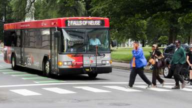 Group of walkers on a cross walk with a GoRaleigh bus in the background