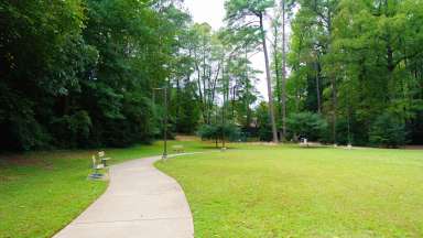 Paved path with park benches leading to playground in distance