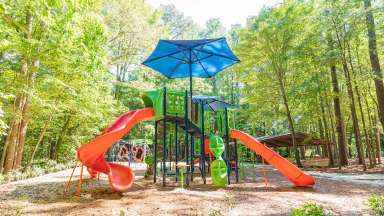 Playground equipment in foreground with picnic shelter and bench in background