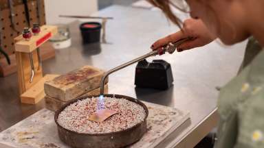 Student uses torch to work on metal piece