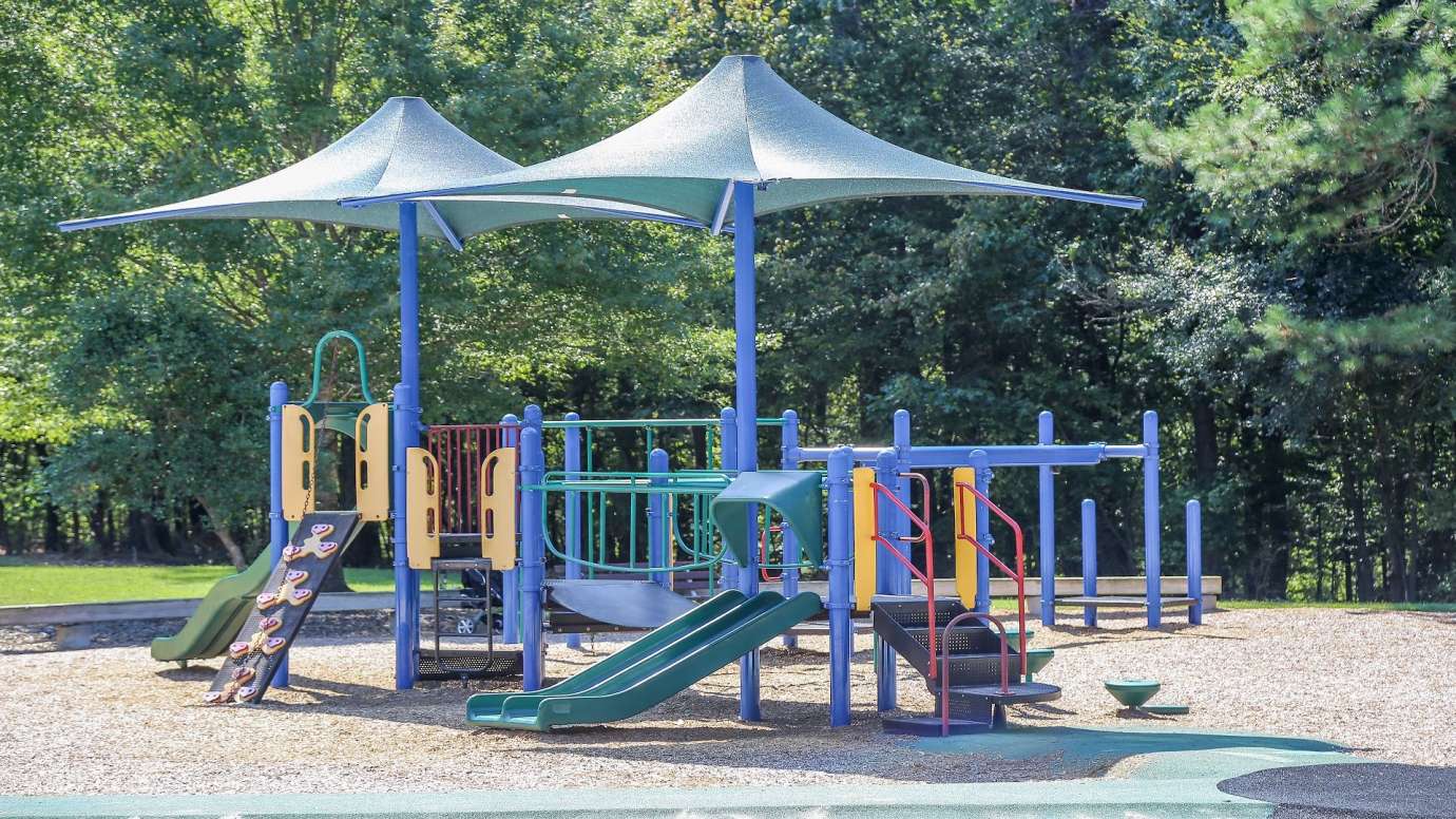 playground structure with slides and other climbing equipment under a canopy