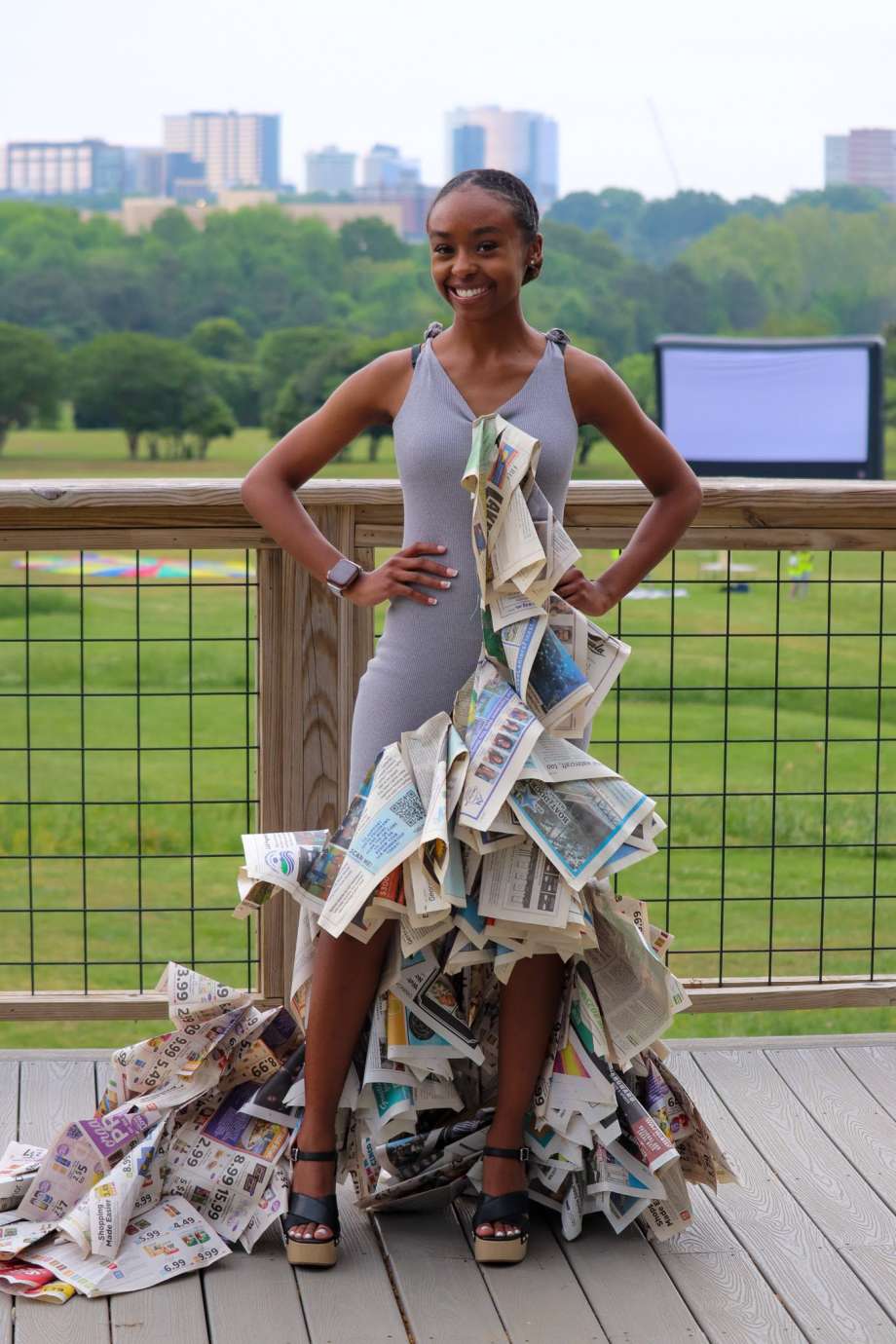 College student stands in front of Raleigh Skyline wearing her trashion outfit