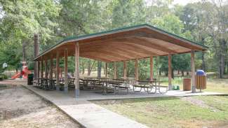 A large outdoor picnic shelter with several tables near the playground at Worthdale Park