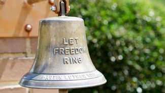 A bell which reads "let freedom ring" at the MLK Gardens