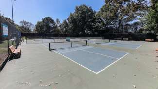 A set of six pickleball courts with nets and backboards