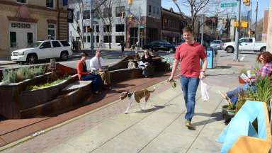 man walking dog through parklet downtown