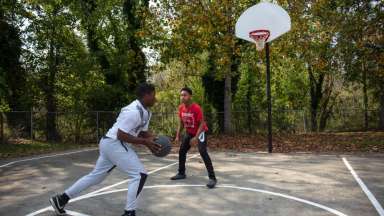 Two teen boys playing basketball on outdoor court at Apollo Heights Park