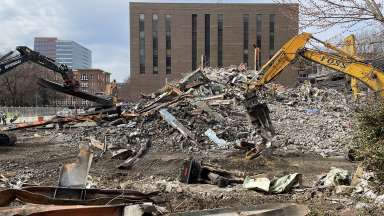 Large machines sifting through the pile of rubble from the old police HQ