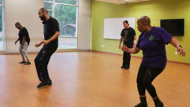 Dancers doing Soul Train Hip Hop in a brightly lit room.