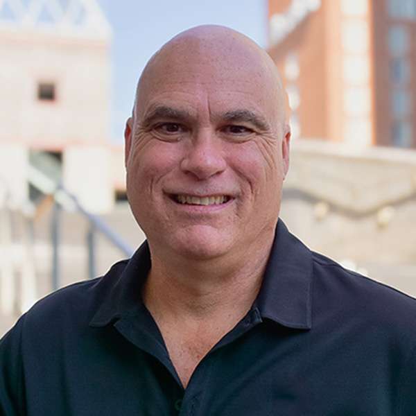 Headshot of John Holden with city buildings in background