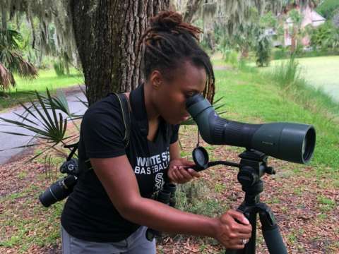 Woman looking through a bird spotting scope.