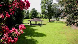 medium sized round picnic shelter with grass and flowers in bloom around it.