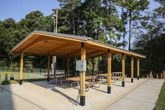 An outdoor covered picnic shelter with multiple tables