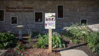 Pollinator garden beside woodland center building with sign