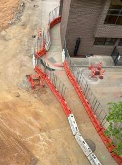 Image shows the back of RMB with the pedestrian detour in place. Detour goes from back do to the left towards the parking deck stairs. 